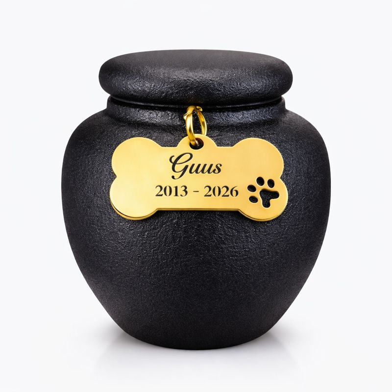 Zwarte keramische mini dierenurn met matte afwerking, ronde vorm en deksel, voorzien van gouden pootafdruk en engelenvleugel.