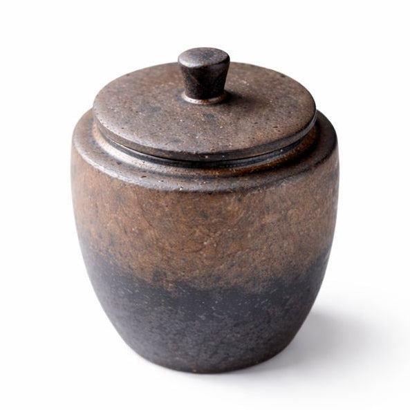 Keramische dierenurn in donkerbruin met subtiele kleurverloop naar grijzer aan de onderzijde, voorzien van deksel en een goudkleurig hartje met pootafdruk