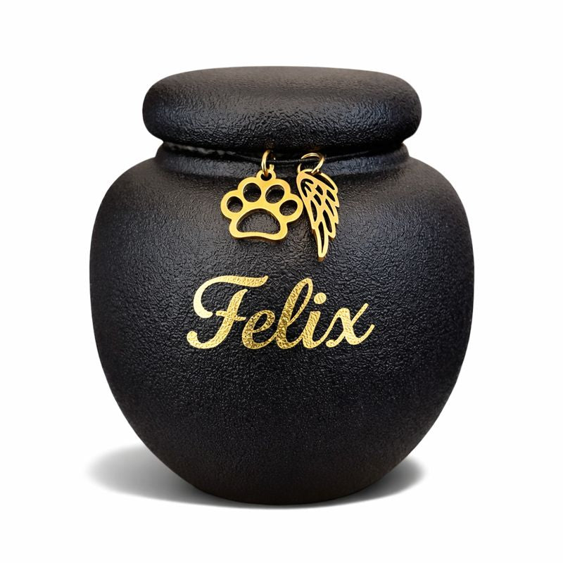 Zwarte keramische mini dierenurn met matte afwerking, ronde vorm en deksel, voorzien van gouden pootafdruk en engelenvleugel.