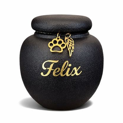 Zwarte keramische mini dierenurn met matte afwerking, ronde vorm en deksel, voorzien van gouden pootafdruk en engelenvleugel.