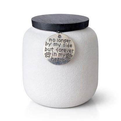 Witte keramische dierenurn met zwarte deksel en herdenkingshanger met pootafdruk.