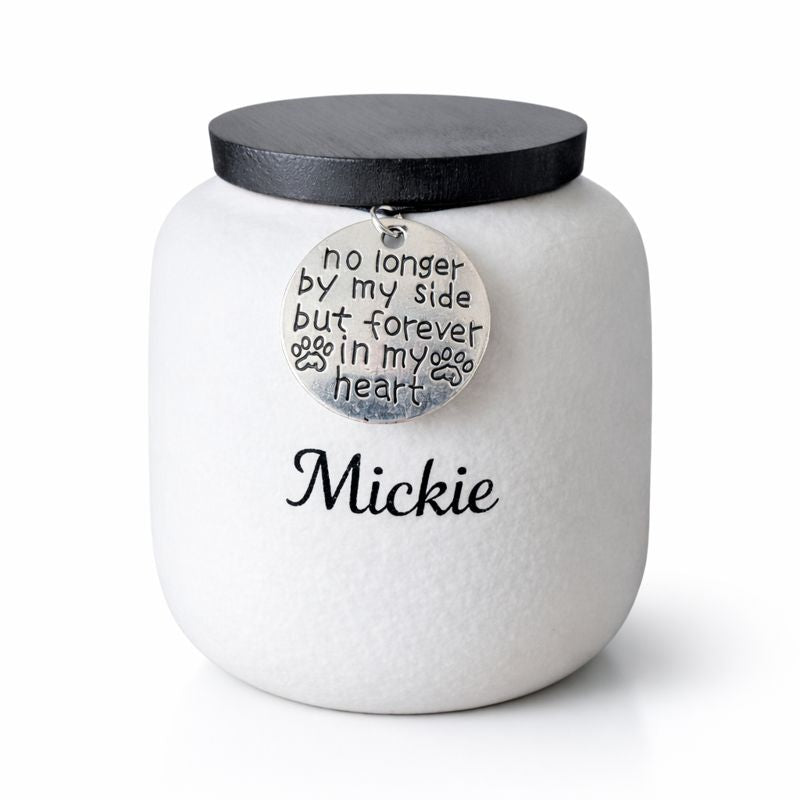 Witte keramische dierenurn met zwarte deksel en herdenkingshanger met pootafdruk.