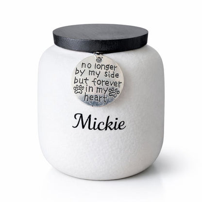 Witte keramische dierenurn met zwarte deksel en herdenkingshanger met pootafdruk.