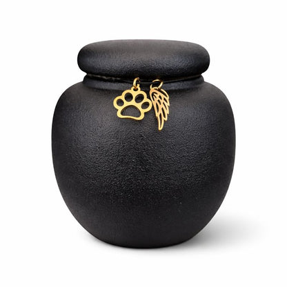 Zwarte keramische mini dierenurn met matte afwerking, ronde vorm en deksel, voorzien van gouden pootafdruk en engelenvleugel.