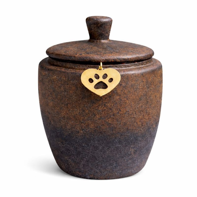 Keramische dierenurn in donkerbruin met subtiele kleurverloop naar grijzer aan de onderzijde, voorzien van deksel en een goudkleurig hartje met pootafdruk