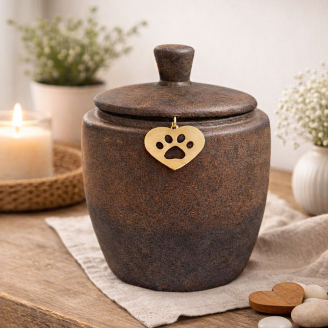 Keramische dierenurn in donkerbruin met subtiele kleurverloop naar grijzer aan de onderzijde, voorzien van deksel en een goudkleurig hartje met pootafdruk