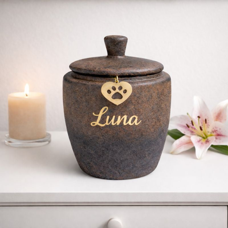 Keramische dierenurn in donkerbruin met subtiele kleurverloop naar grijzer aan de onderzijde, voorzien van deksel en een goudkleurig hartje met pootafdruk, met naam huisdier