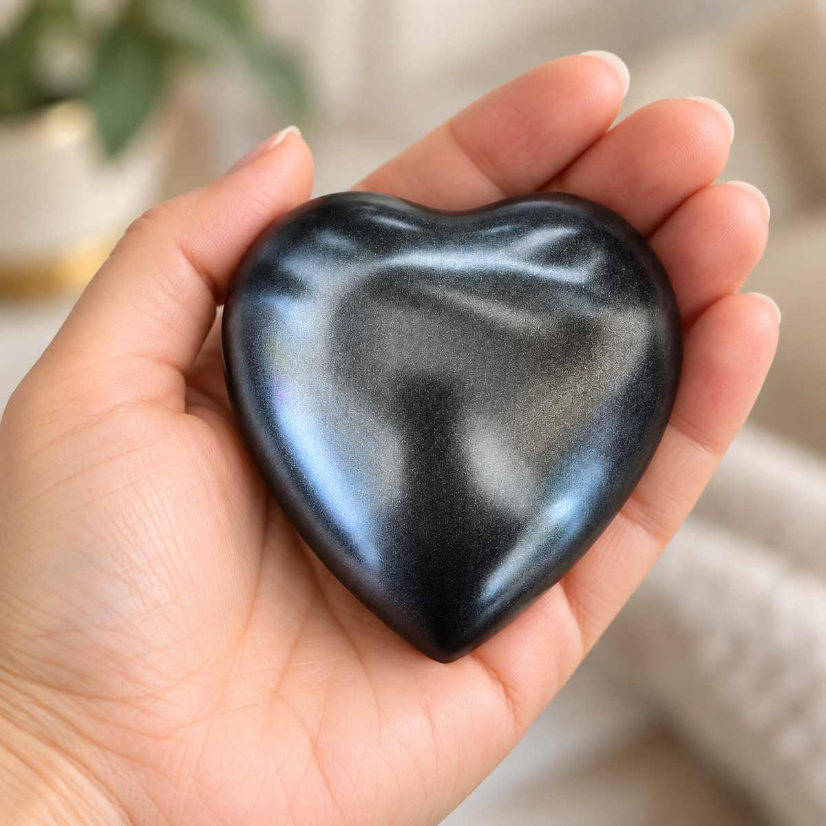 De laatste aai antraciet hartvormige mini urn van aluminium met subtiele glinstering in een handpalm.