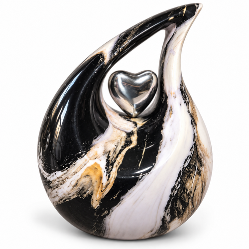 De laatste aai druppel urn met marmerlook in zwart, wit en goud met een glanzend zilveren hart als symbool van liefde.