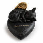 De laatste aai hartvormige urn voor katten in zwart resin met een slapend katje en gouden engelenvleugels.