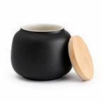 De laatste aai zwarte keramische mini-urn voor katten met een natuurlijk bamboe deksel op een witte achtergrond