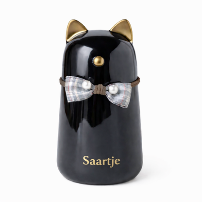 Katten urn met naam - gemaakt van zwart keramiek, met goudkleurige details en is voorzien van een schattig strikje